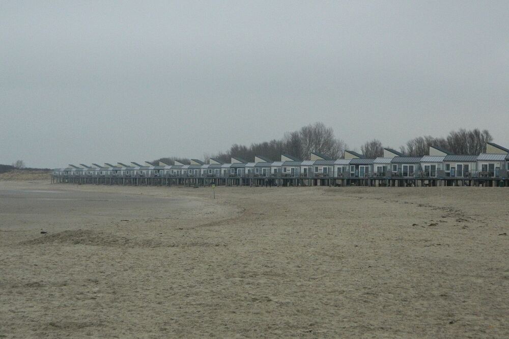 Het brede strand bij Kamperland met een rij strandhuisjes langs de duinrand